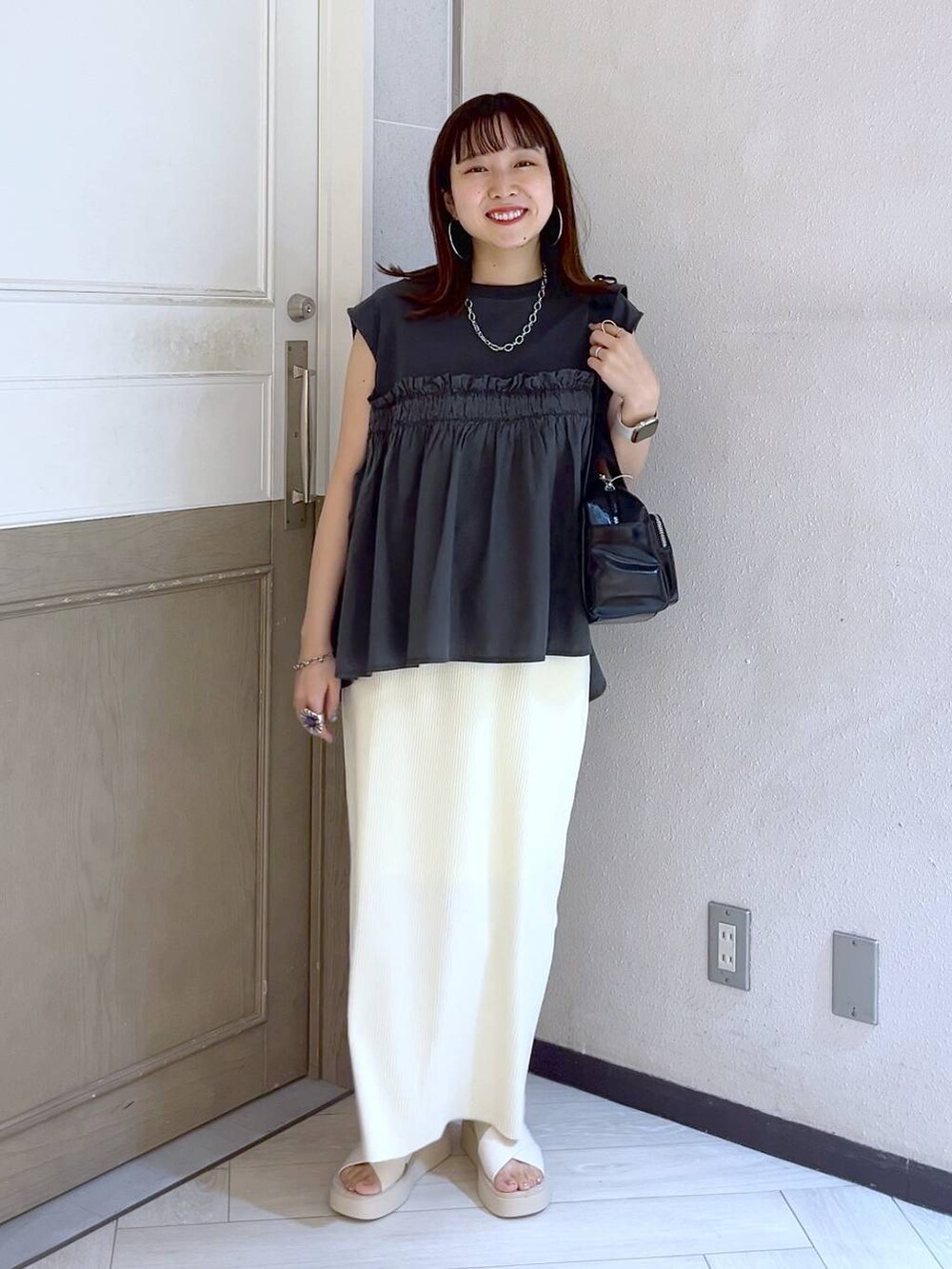 ホワイト系のスカート、ホワイト系のサンダル、ブラック系のボストンバッグを着用したレディースの夏コーディネートの2枚目の写真