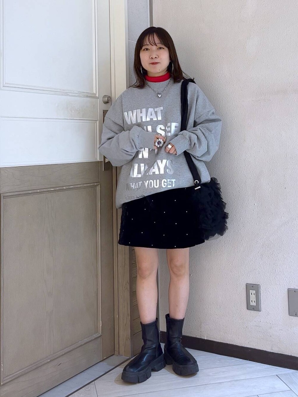 ブラック系のブーツ、レッド系のニット/セーター、ブラック系のショルダーバッグを着用したレディースの冬コーディネートの2枚目の写真