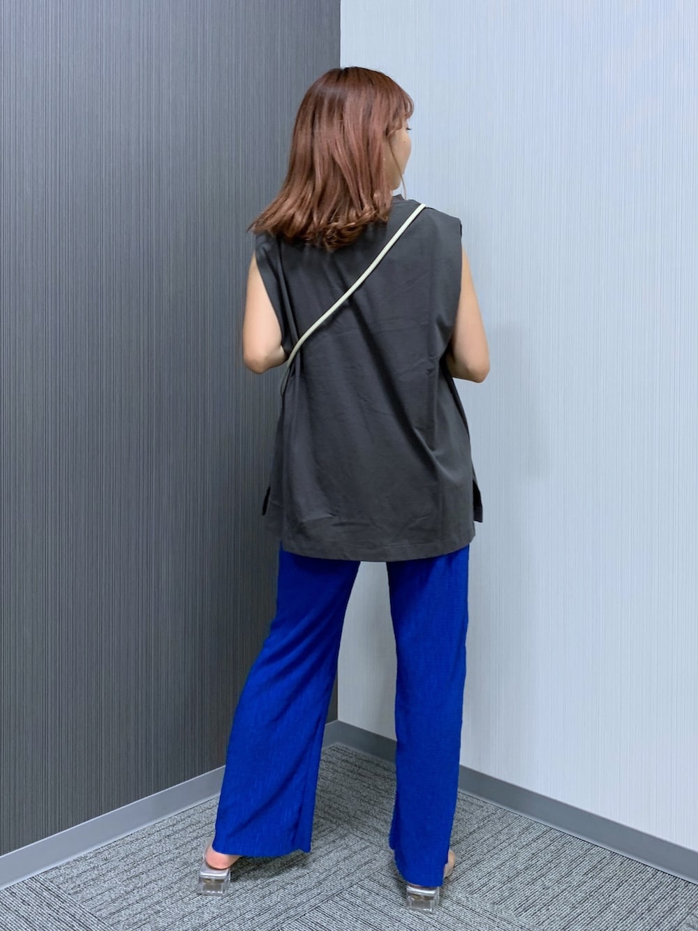 グレー系のトップス、ブルー系のパンツ、ホワイト系のショルダーバッグを着用したレディースの夏コーディネートの2枚目の写真