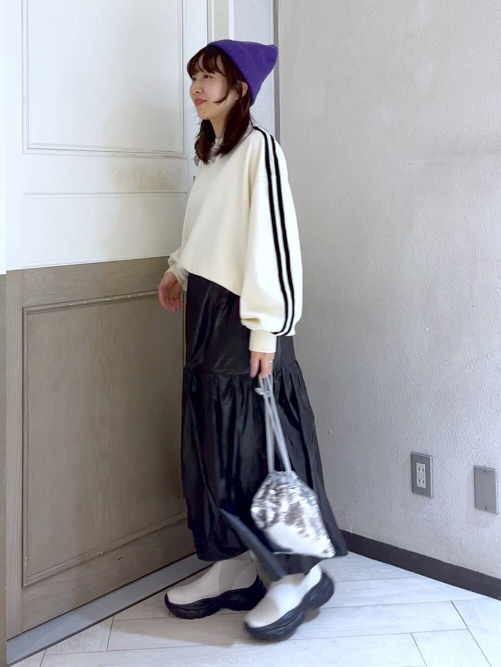 シルバー系のハンドバッグ、ホワイト系のスウェット、ホワイト系のブーツを着用したレディースの冬コーディネートの3枚目の写真