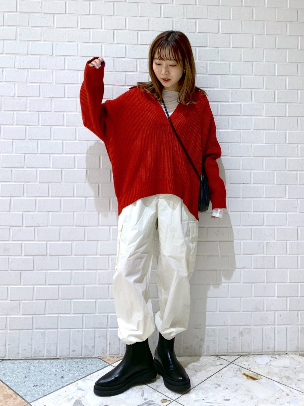 オレンジ系のトップス、ホワイト系のパンツ、ブラック系のバッグを着用したレディースの秋コーディネートの3枚目の写真