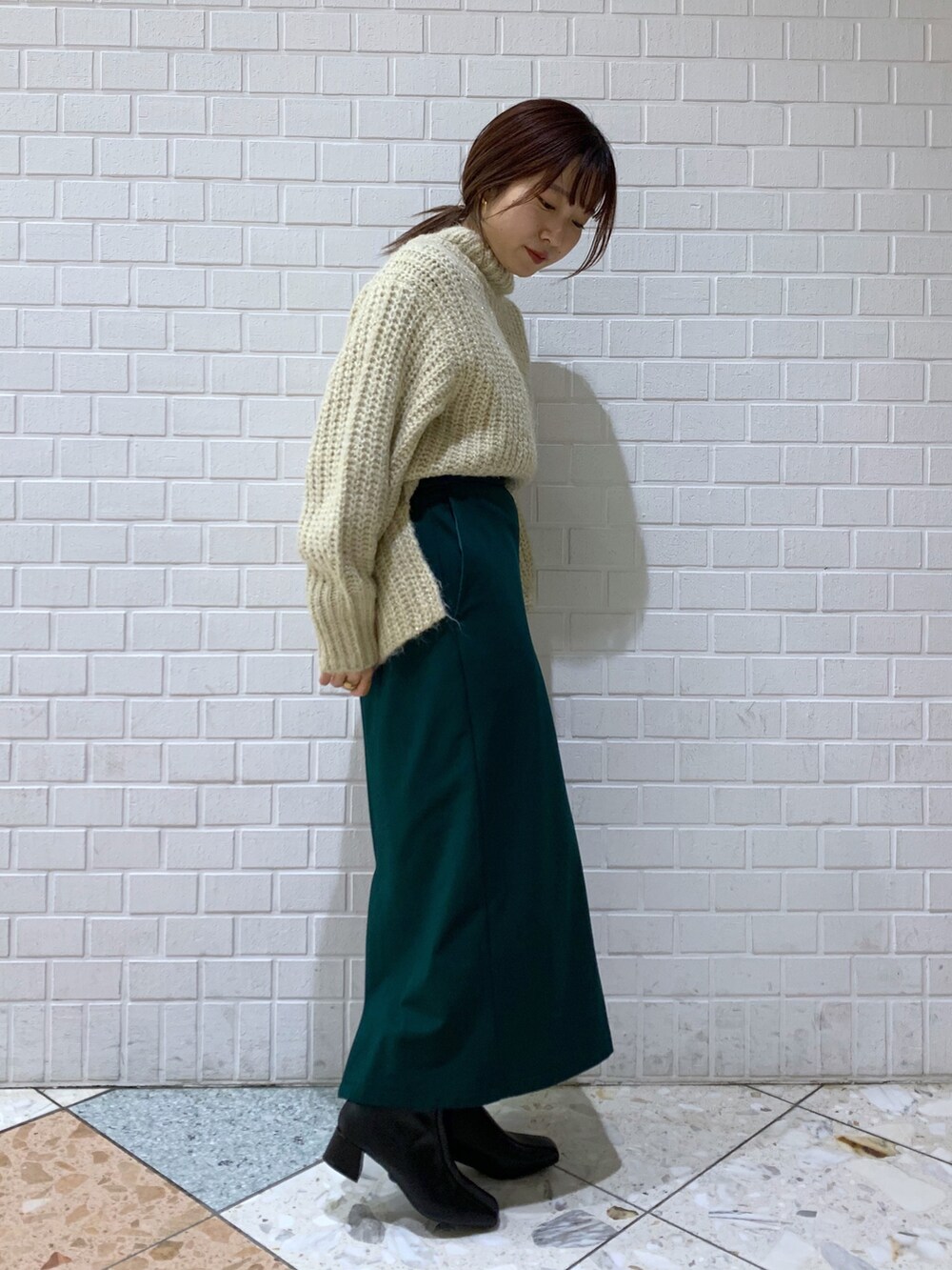 ホワイト系のトップス、グリーン系のスカート、ブラック系のバッグを着用したレディースの冬コーディネートの2枚目の写真