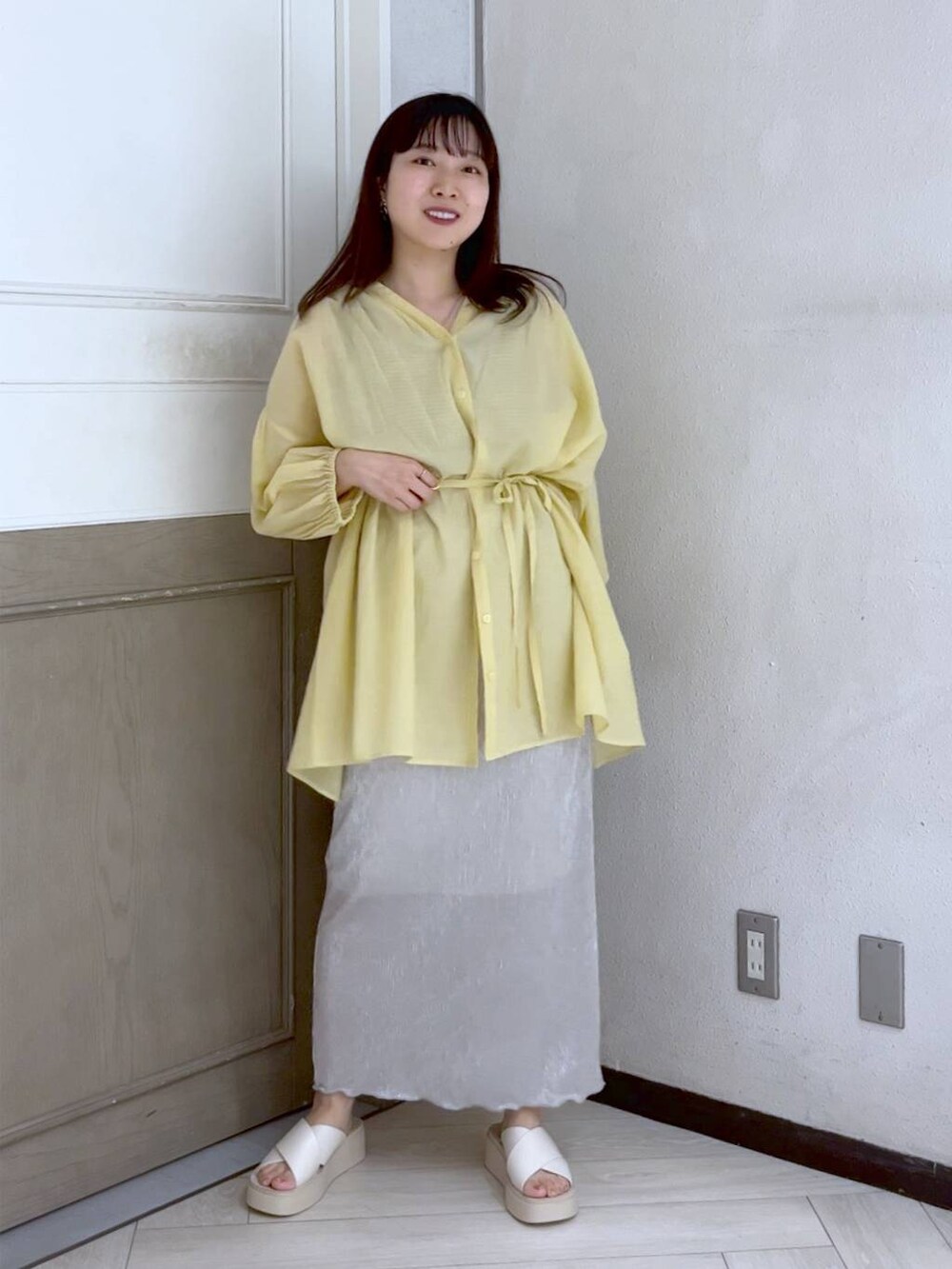 イエロー系のシャツ/ブラウス、ホワイト系のスカート、ホワイト系のサンダルを着用したレディースの夏コーディネートの2枚目の写真
