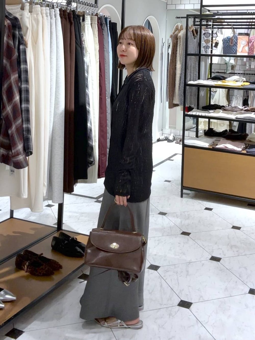 シルバー系のサンダル、グレー系のスカート、ブラック系のボストンバッグを着用したレディースの夏コーディネートの2枚目の写真