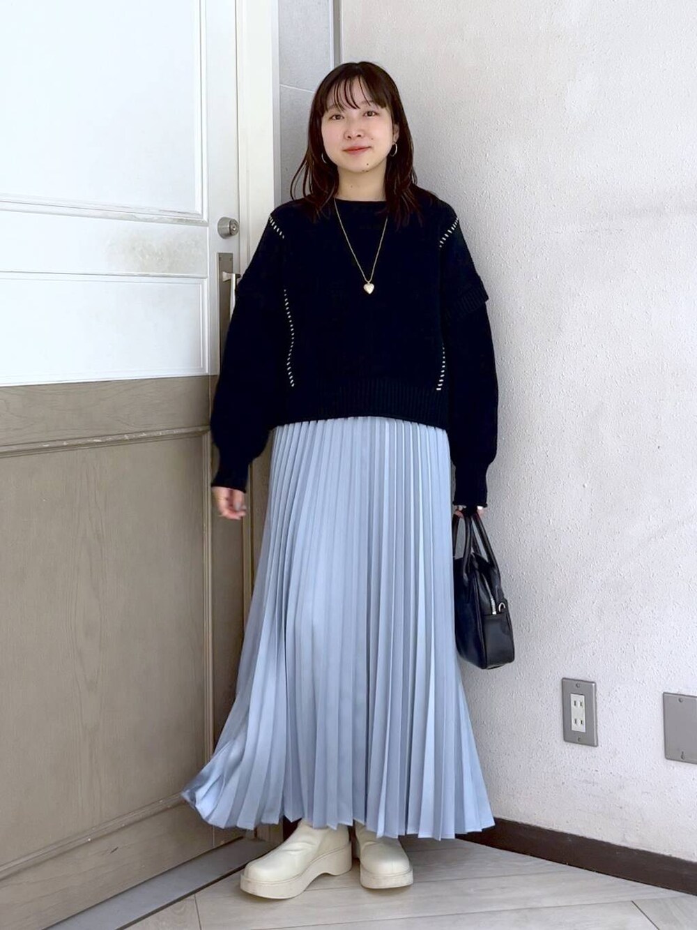 ブラック系のTシャツ/カットソー、ホワイト系のブーツ、ブラック系のボストンバッグを着用したレディースの冬コーディネートの2枚目の写真