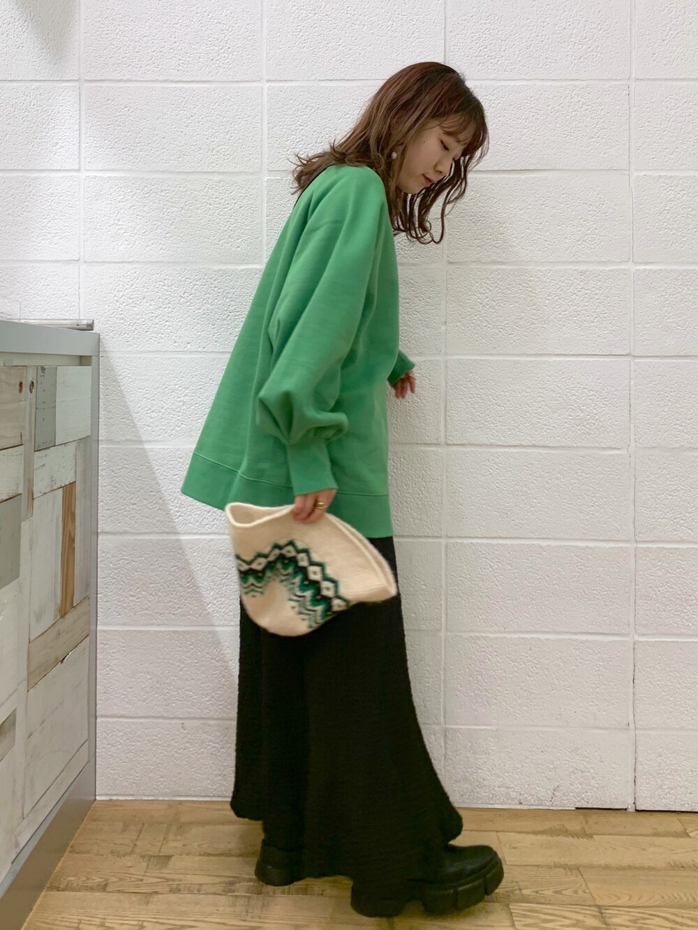 グリーン系のトップス、ブラック系のスカート、ブラック系のバッグを着用したレディースの秋コーディネートの2枚目の写真