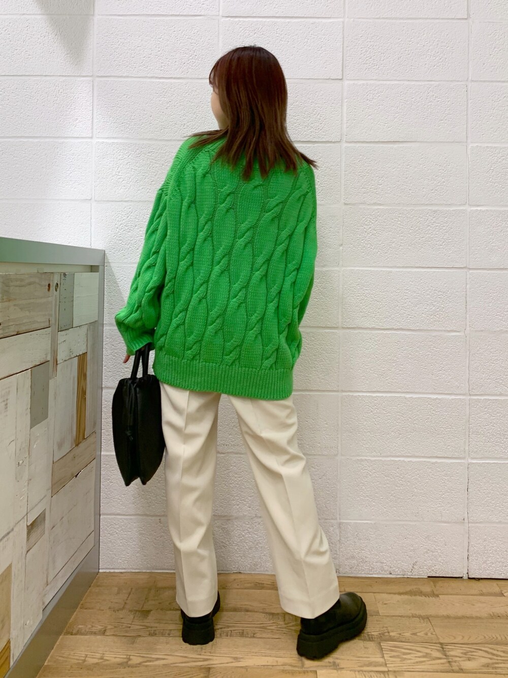 グリーン系のトップス、ブラック系のショルダーバッグ、ブルー系のパンツを着用したレディースの秋コーディネートの3枚目の写真