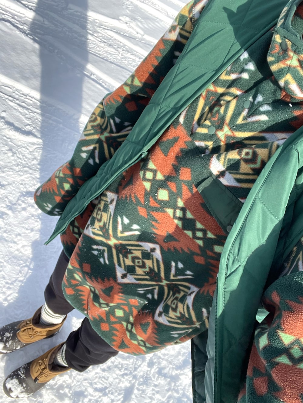 グリーン系のスウェット、グリーン系のベスト、ブラック系のスウェットパンツを着用したレディースの冬コーディネートの2枚目の写真