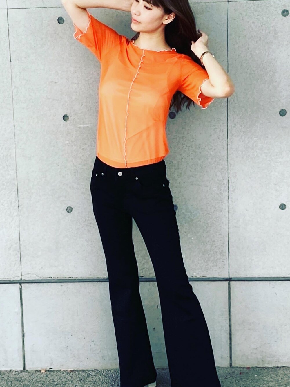 オレンジ系のTシャツ/カットソー、ブラック系のデニムパンツを着用したレディースの夏コーディネートの2枚目の写真