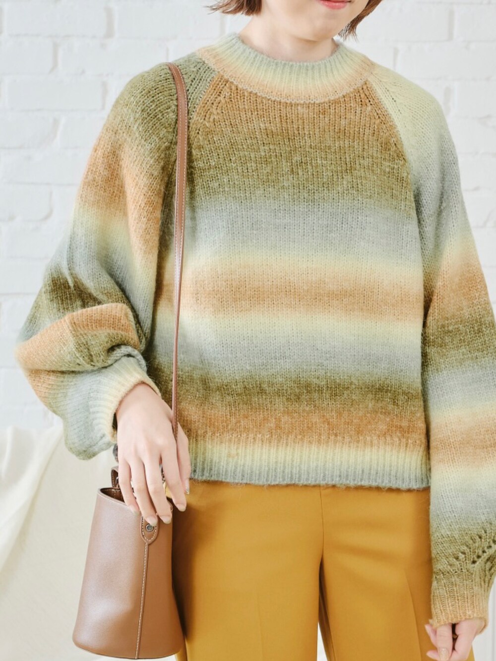 オレンジ系のニット/セーター、ブルー系のデニムパンツを着用したレディースの秋コーディネートの3枚目の写真