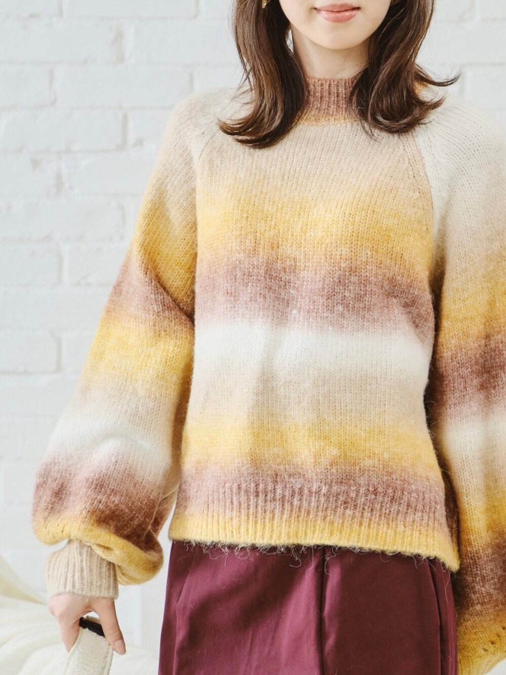 オレンジ系のニット/セーター、ブルー系のデニムパンツを着用したレディースの秋コーディネートの2枚目の写真