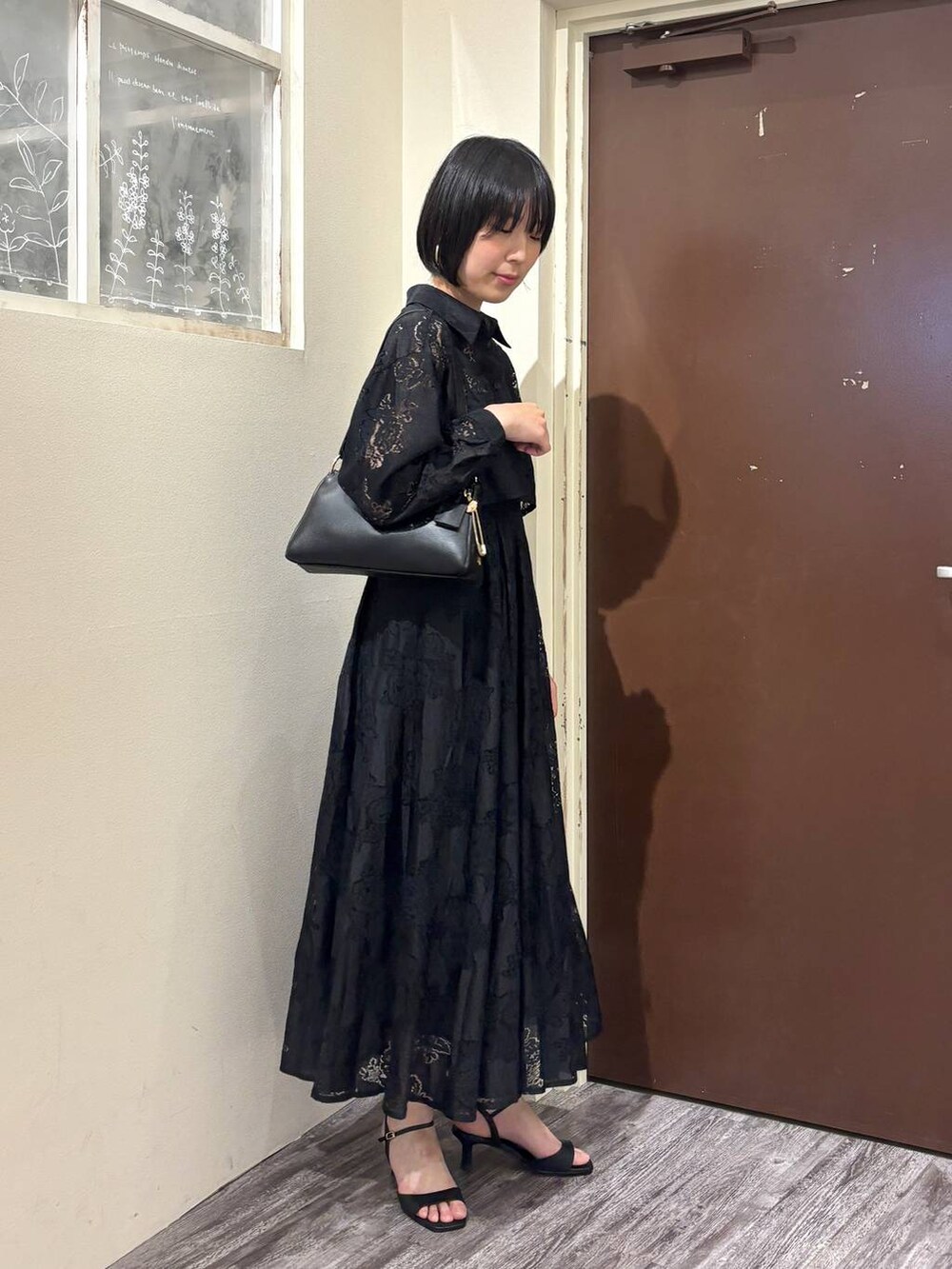 ブラック系のワンピース、ブラック系のショルダーバッグ、ブラック系のサンダルを着用したレディースの春コーディネートの4枚目の写真
