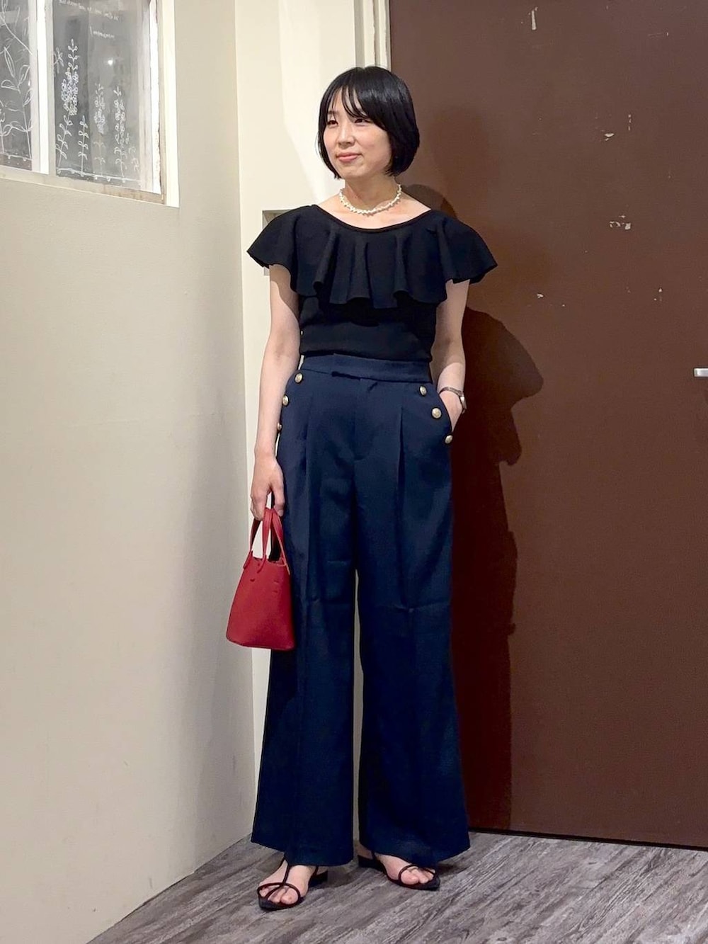 ブラック系のニット/セーター、ブルー系のその他パンツ、ホワイト系のネックレスを着用したレディースの春コーディネートの2枚目の写真