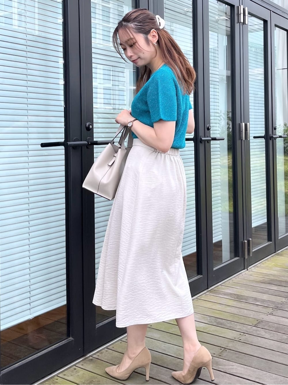 ブルー系のニット/セーター、グレー系のスカート、グレー系のトートバッグを着用したレディースの夏コーディネートの5枚目の写真