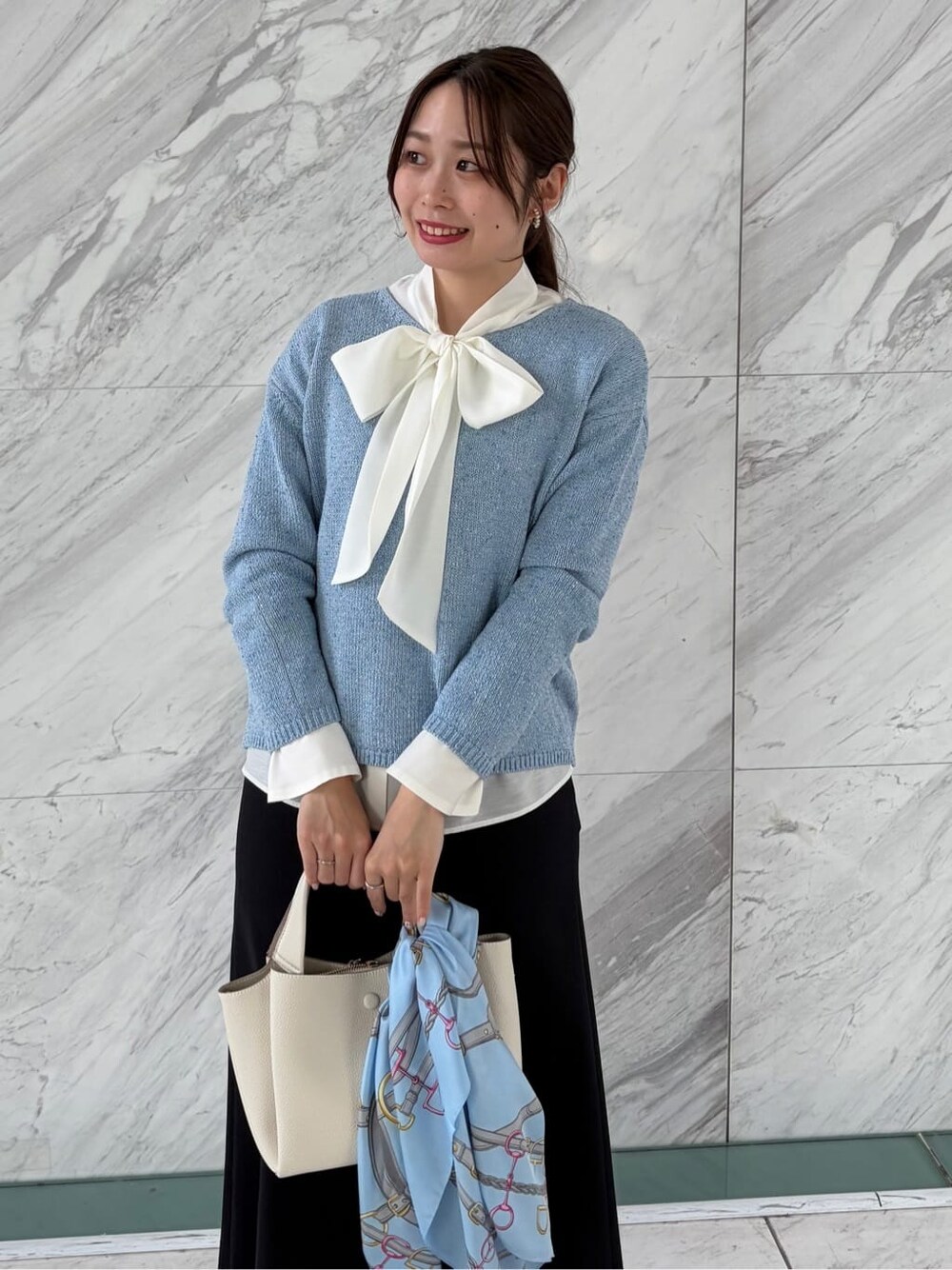 ブルー系のニット/セーター、ホワイト系のシャツ/ブラウス、ブルー系のスカートを着用したレディースの春コーディネートの7枚目の写真