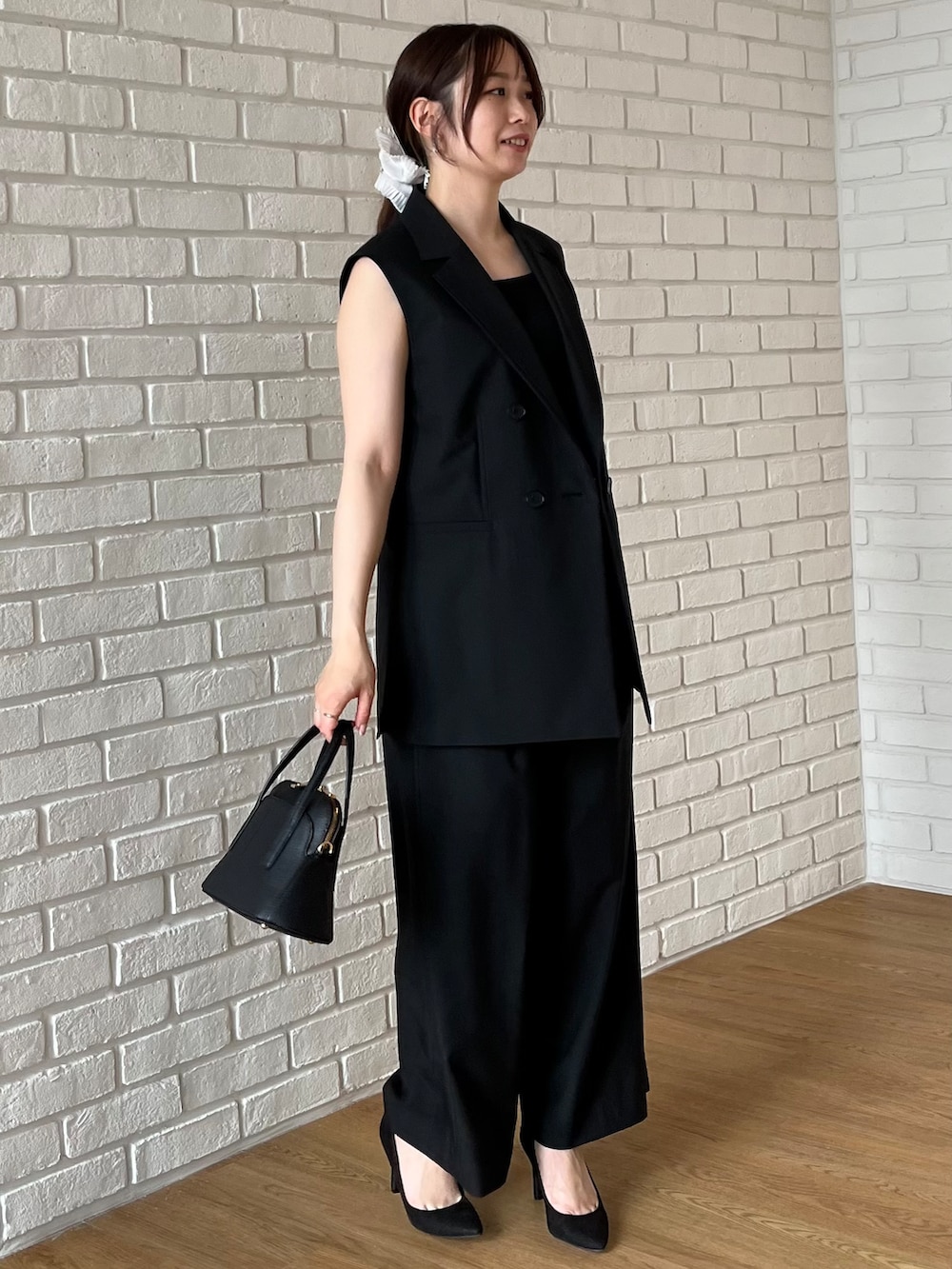 ブラック系のニット/セーター、ブラック系のショルダーバッグを着用したレディースの夏コーディネートの5枚目の写真