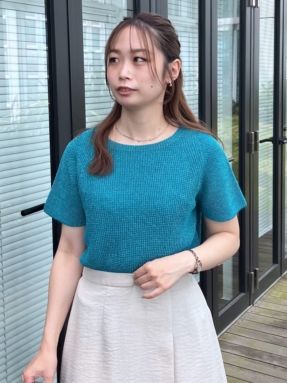 ブルー系のニット/セーター、グレー系のスカート、グレー系のトートバッグを着用したレディースの夏コーディネートの8枚目の写真