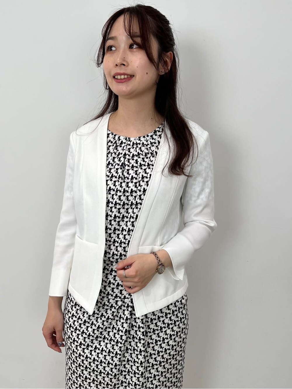 ブラック系のTシャツ/カットソー、ブラック系のスカート、ホワイト系のノーカラージャケットを着用したレディースの春コーディネートの7枚目の写真