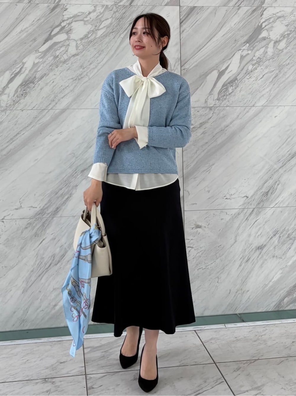 ブルー系のニット/セーター、ホワイト系のシャツ/ブラウス、ブルー系のスカートを着用したレディースの春コーディネートの2枚目の写真