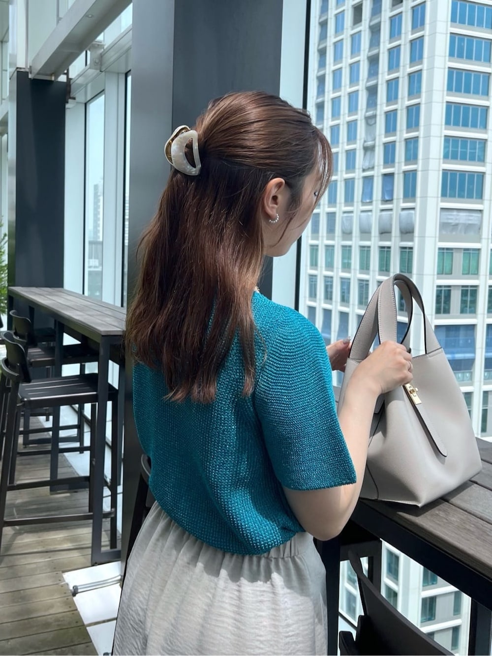 ブルー系のニット/セーター、グレー系のスカート、グレー系のトートバッグを着用したレディースの夏コーディネートの9枚目の写真