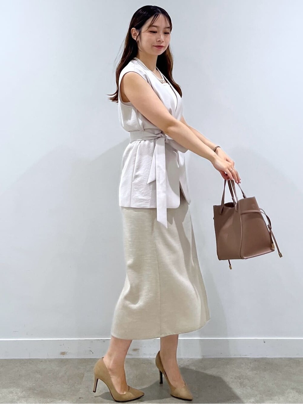 ベージュ系のベスト、ホワイト系のタンクトップ、ブラウン系のトートバッグを着用したレディースの夏コーディネートの4枚目の写真