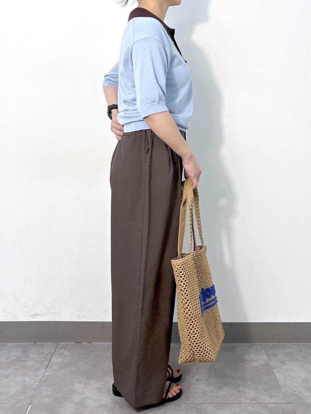 ブルー系のニット/セーター、ブラウン系のその他パンツ、ベージュ系のトートバッグを着用したレディースの夏コーディネートの4枚目の写真
