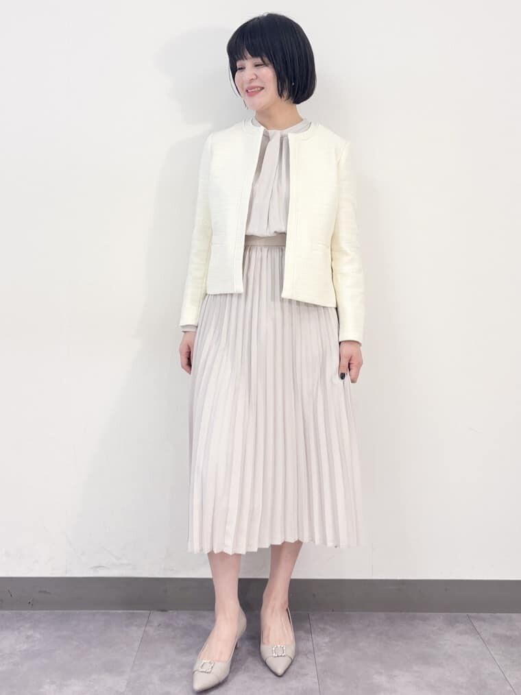 ホワイト系のノーカラージャケット、ベージュ系のワンピース、ベージュ系のパンプスを着用したレディースの冬コーディネートの6枚目の写真