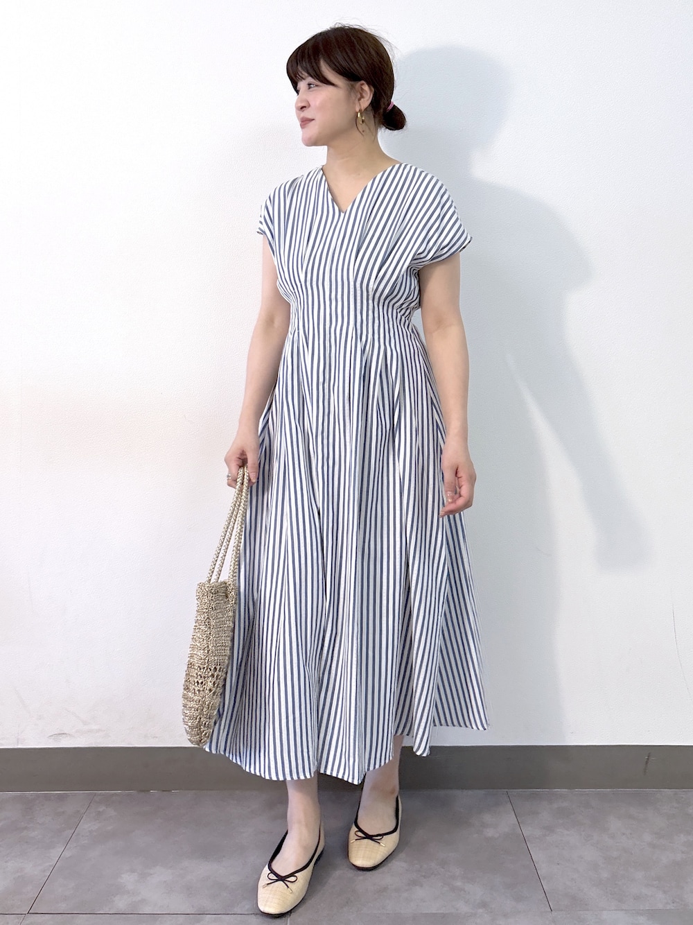 ブルー系のワンピース、ゴールド系のトートバッグ、ベージュ系のパンプスを着用したレディースの夏コーディネートの2枚目の写真