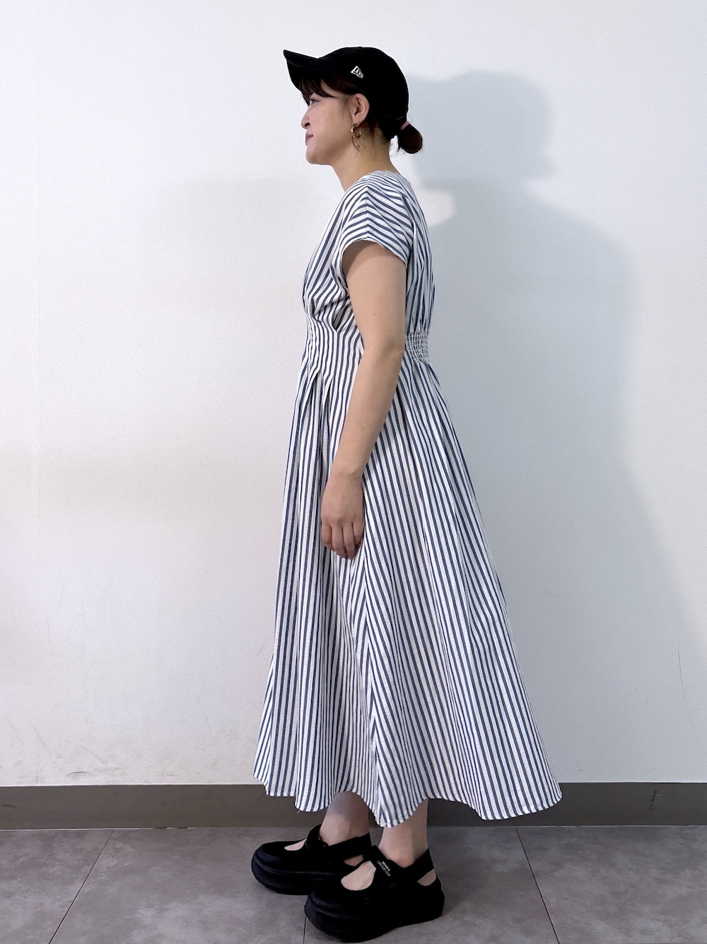ブルー系のワンピース、ゴールド系のトートバッグ、ベージュ系のパンプスを着用したレディースの夏コーディネートの4枚目の写真