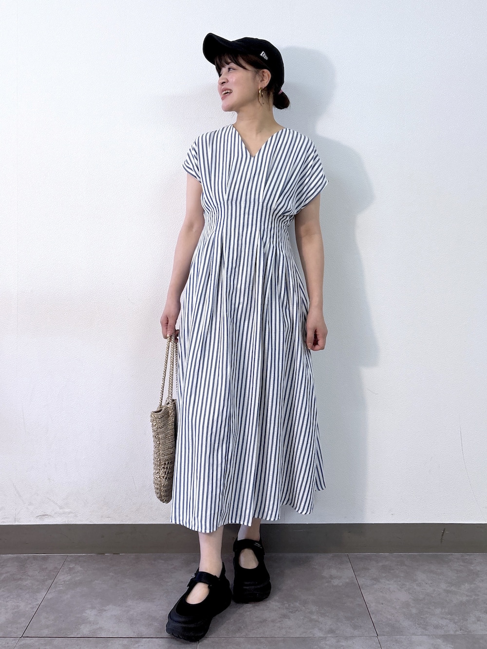 ブルー系のワンピース、ゴールド系のトートバッグ、ベージュ系のパンプスを着用したレディースの夏コーディネートの5枚目の写真