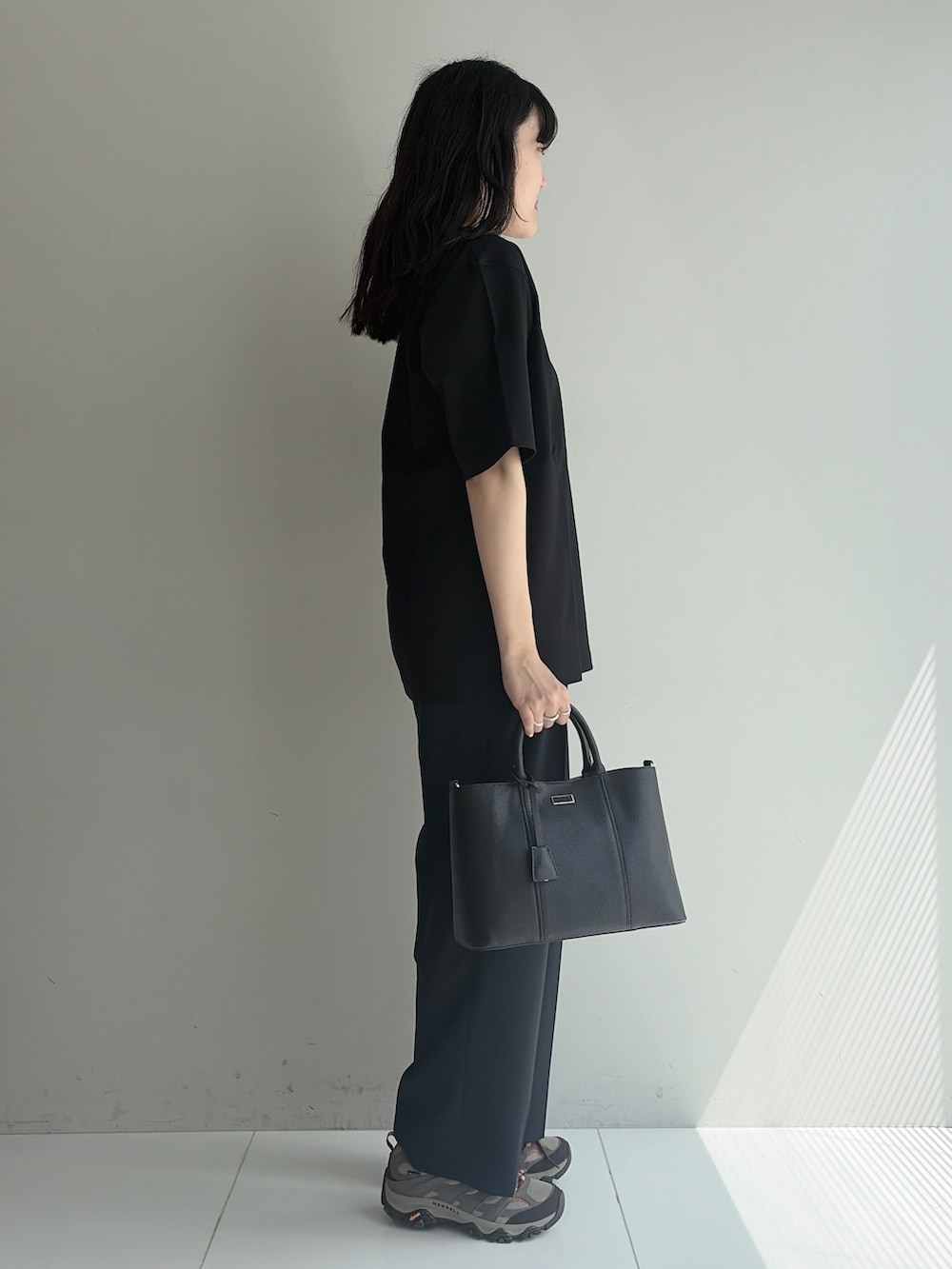 ブルー系のスラックス、ブラック系のトートバッグ、ブラック系のTシャツ/カットソーを着用したメンズの春コーディネートの4枚目の写真
