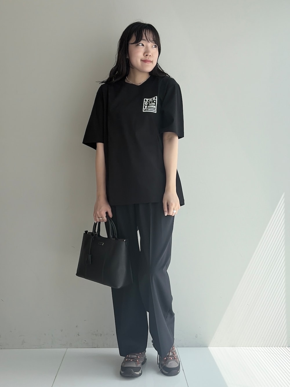 ブルー系のスラックス、ブラック系のトートバッグ、ブラック系のTシャツ/カットソーを着用したメンズの春コーディネートの5枚目の写真