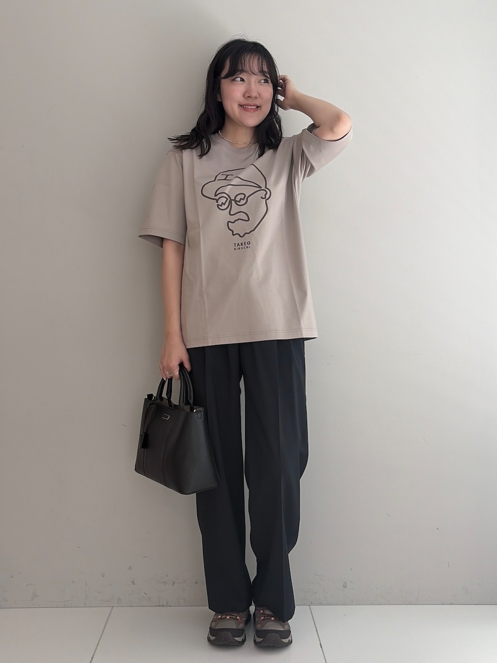 ブルー系のスラックス、ブラック系のトートバッグ、ベージュ系のTシャツ/カットソーを着用したメンズの春コーディネートの5枚目の写真