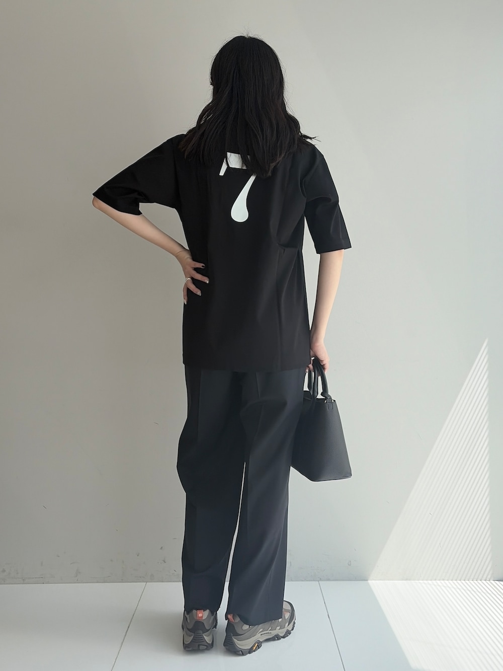 ブルー系のスラックス、ブラック系のトートバッグ、ブラック系のTシャツ/カットソーを着用したメンズの春コーディネートの3枚目の写真