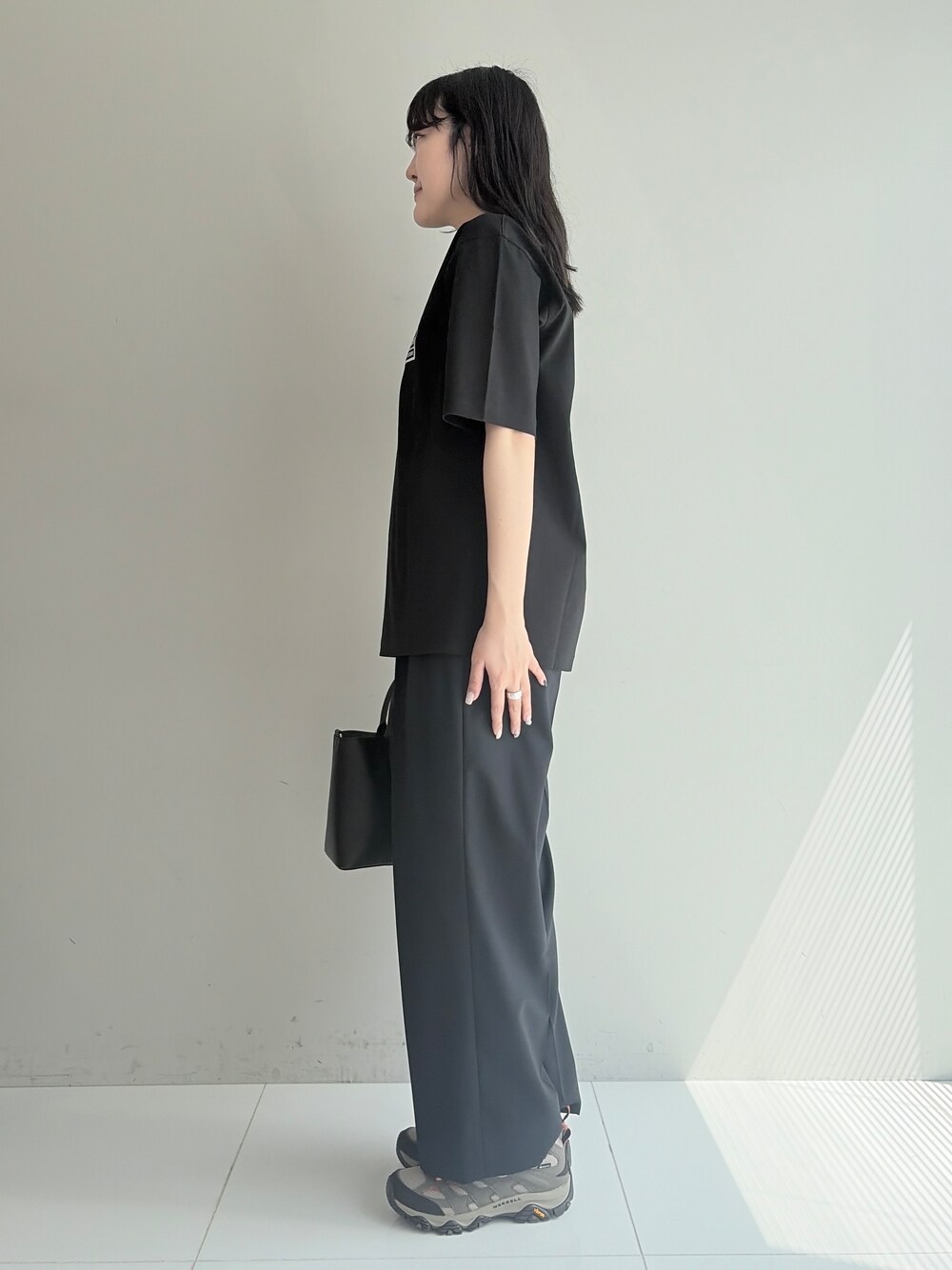 ブルー系のスラックス、ブラック系のトートバッグ、ブラック系のTシャツ/カットソーを着用したメンズの春コーディネートの2枚目の写真