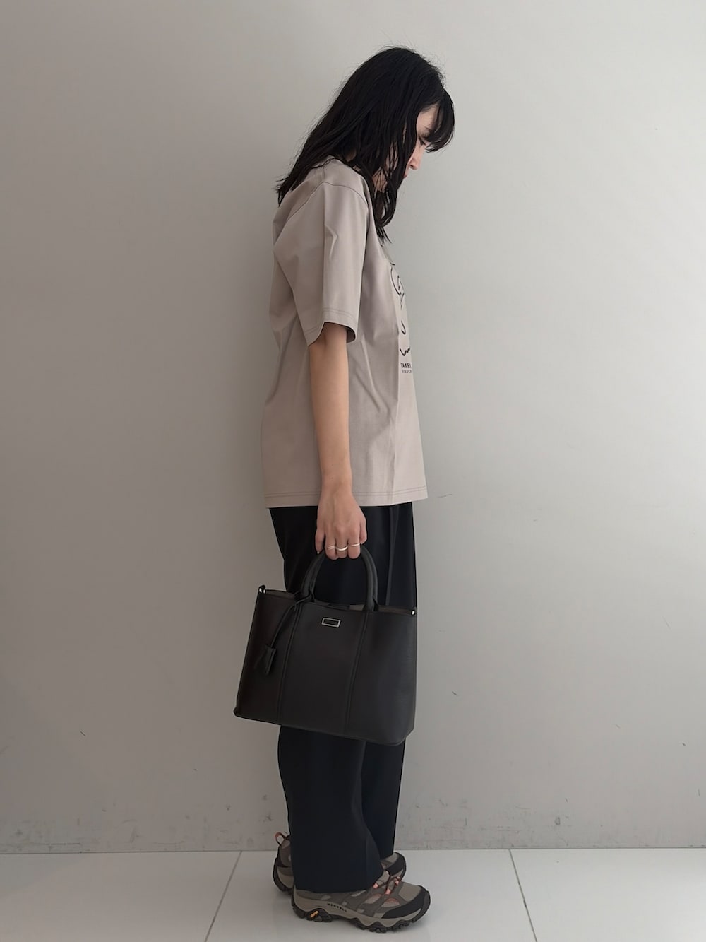 ブルー系のスラックス、ブラック系のトートバッグ、ベージュ系のTシャツ/カットソーを着用したメンズの春コーディネートの4枚目の写真