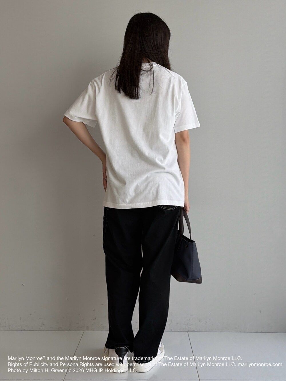 ブラック系のデニムパンツ、ブルー系のトートバッグ、ホワイト系のスニーカーを着用したメンズの夏コーディネートの4枚目の写真