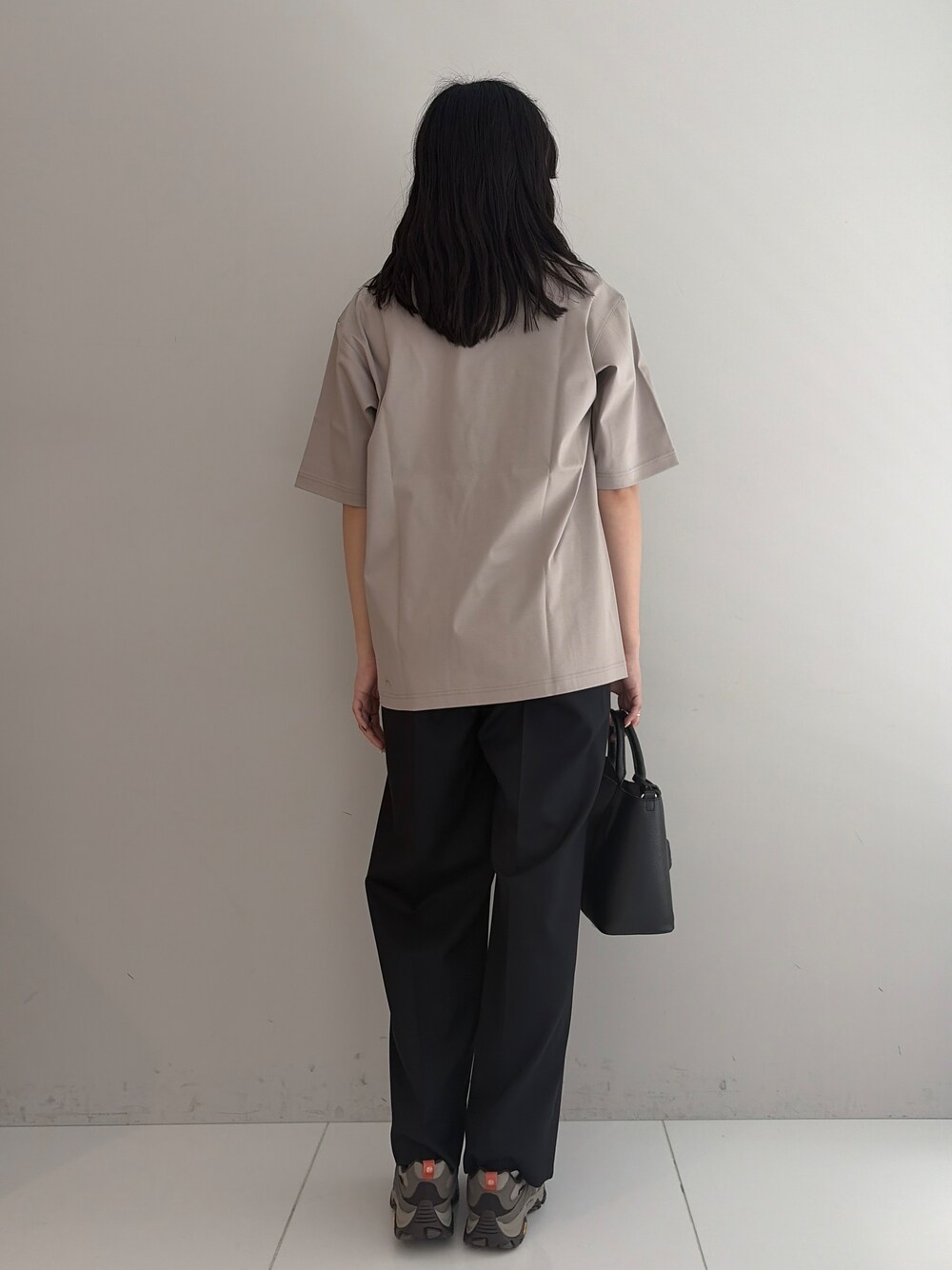 ブルー系のスラックス、ブラック系のトートバッグ、ベージュ系のTシャツ/カットソーを着用したメンズの春コーディネートの3枚目の写真