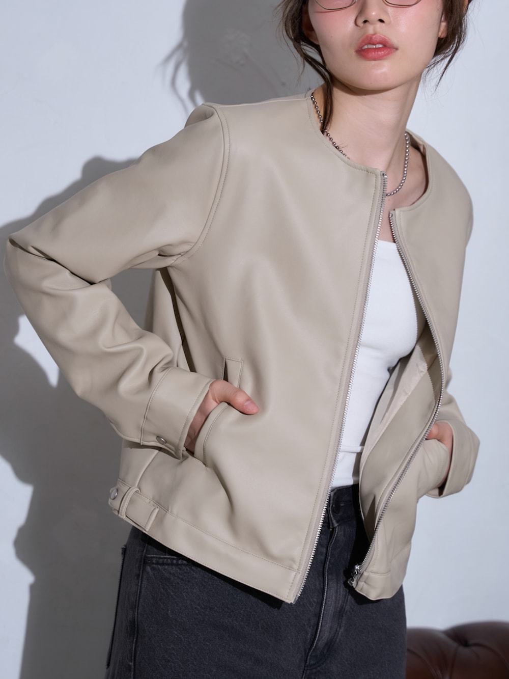 ホワイト系のライダースジャケットを着用したレディースの春コーディネートの2枚目の写真