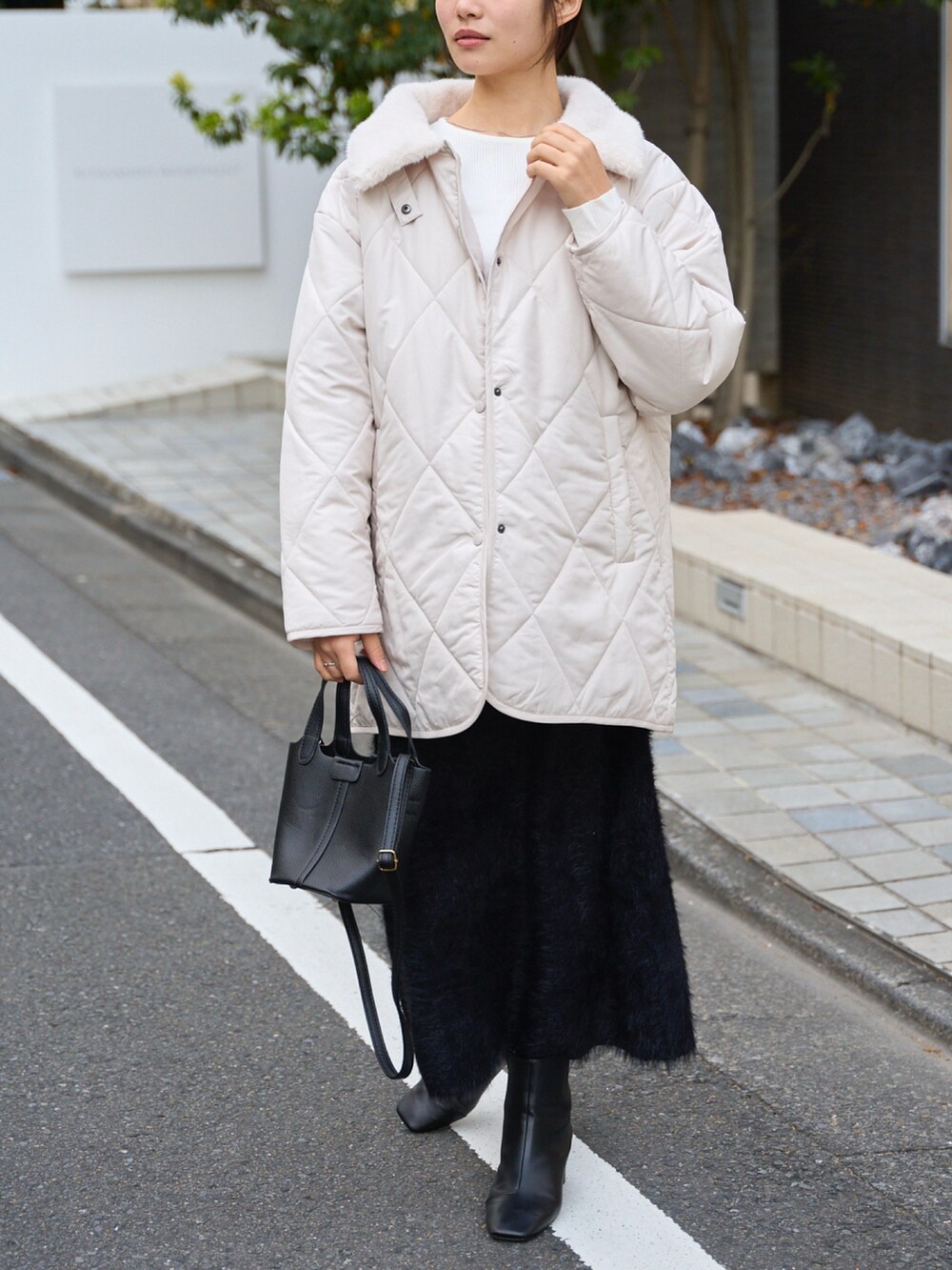 ホワイト系のその他アウター、ブラック系のスカートを着用したレディースの冬コーディネートの2枚目の写真