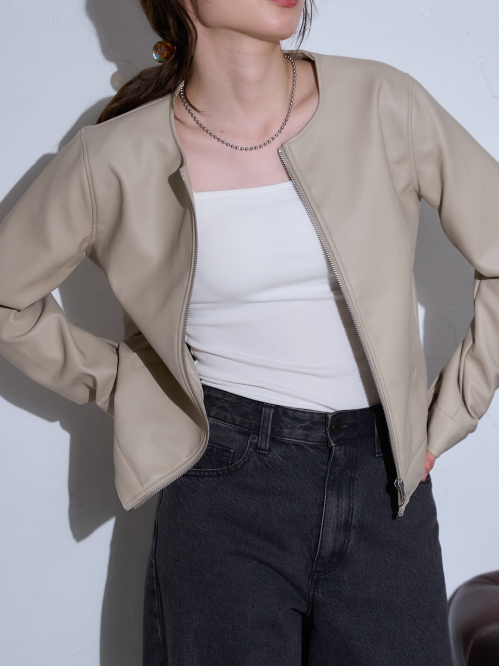 ホワイト系のライダースジャケットを着用したレディースの春コーディネートの3枚目の写真