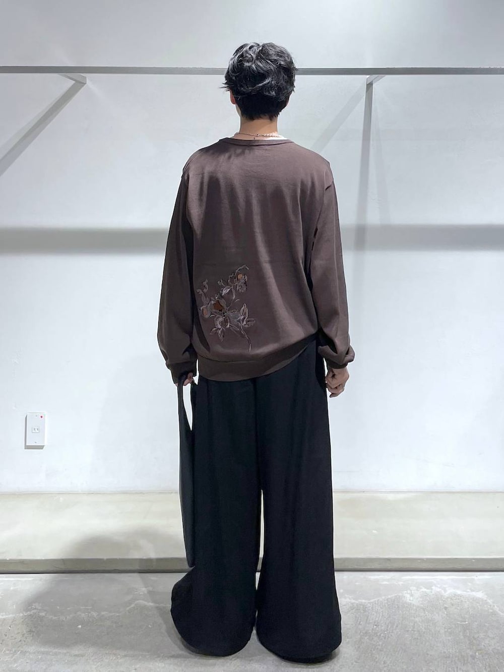 ブラウン系のニット/セーター、ブラック系のトートバッグ、ブラック系のスラックスを着用したメンズの夏コーディネートの3枚目の写真