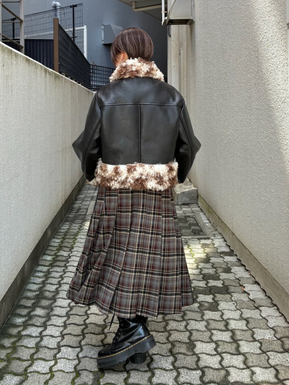ブラック系のムートンコート、ブラック系のTシャツ/カットソー、レッド系のスカートを着用したレディースの秋コーディネートの3枚目の写真