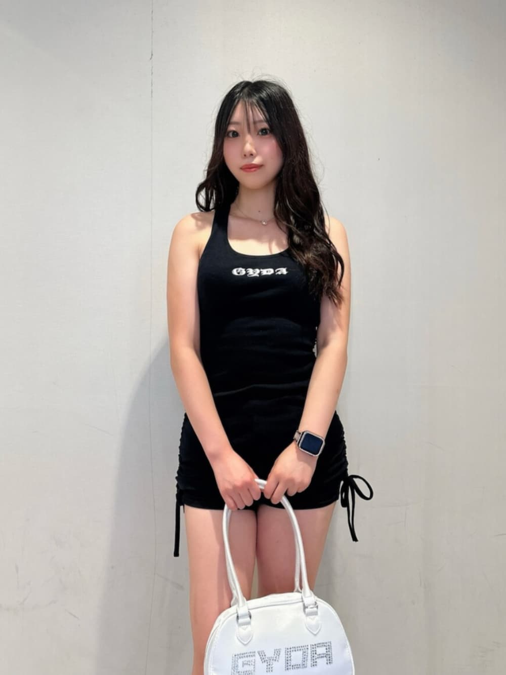 ブラック系のワンピース、ホワイト系のボストンバッグ、ブラック系のブーツを着用したレディースの夏コーディネートの4枚目の写真
