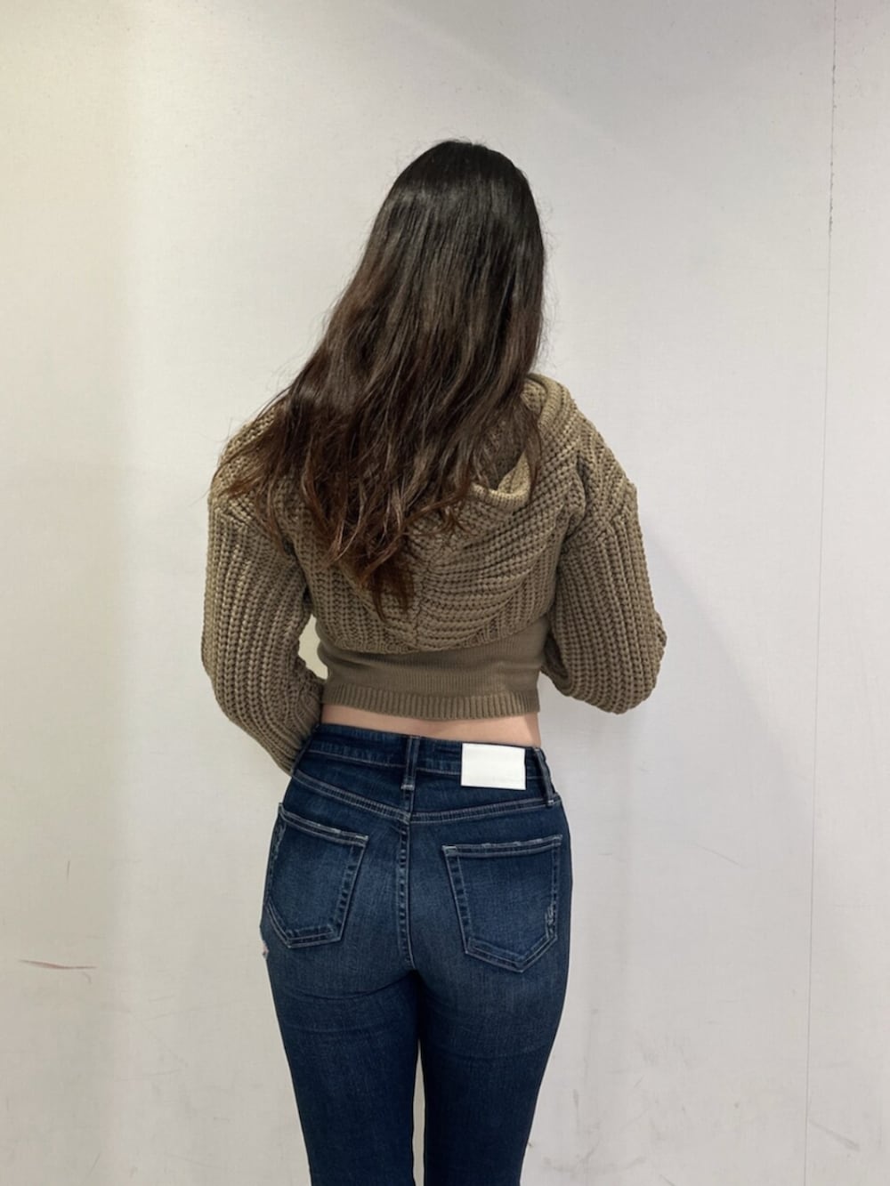 ホワイト系のニット/セーター、ブルー系のデニムパンツ、ブラック系のブーツを着用したレディースの秋コーディネートの6枚目の写真