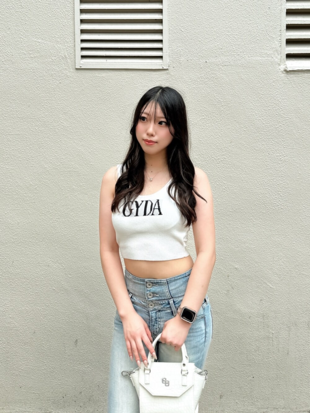 ブルー系のデニムパンツ、ホワイト系のハンドバッグ、ホワイト系のサンダルを着用したレディースの夏コーディネートの4枚目の写真