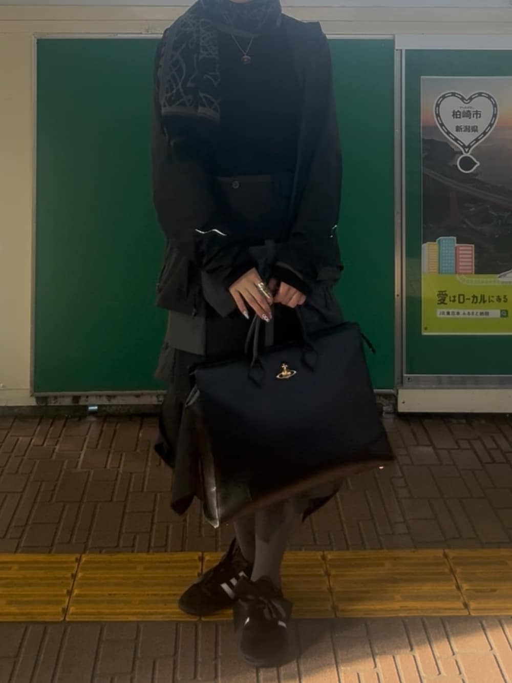 ブラック系のジャケット/アウター、ブラック系のビジネスバッグ、ブラック系のスニーカーを着用したレディースの冬コーディネートの2枚目の写真