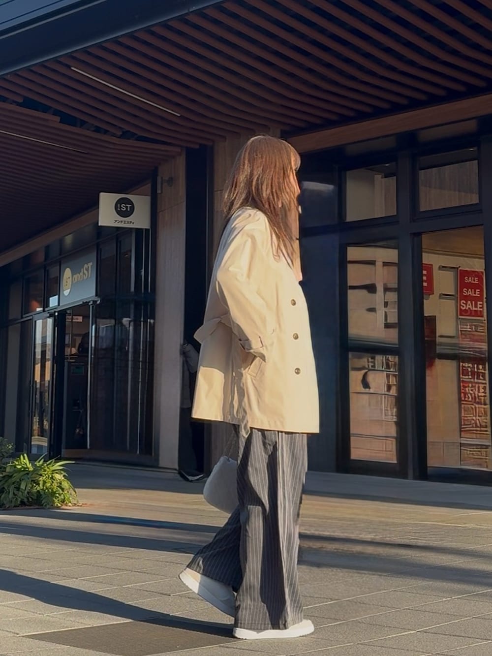 ベージュ系のトレンチコート、ブルー系のTシャツ/カットソー、グレー系のセットアップを着用したレディースの冬コーディネートの2枚目の写真