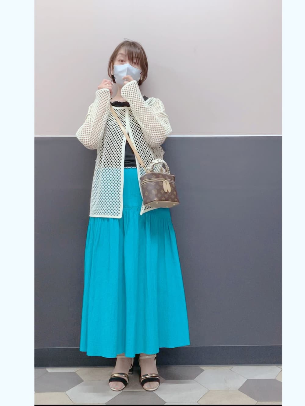ブルー系のスカート、ブラウン系のボディバッグ/ウエストポーチ、ホワイト系のカーディガン/ボレロを着用したレディースの春コーディネートの2枚目の写真