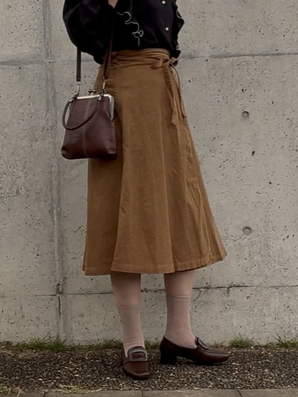 ブラウン系のスカート、ブラウン系のショルダーバッグ、ブラウン系のローファーを着用したレディースの秋コーディネートの2枚目の写真